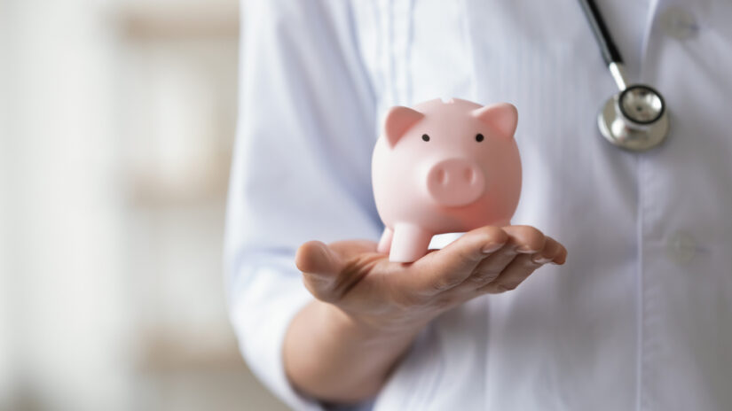 Photo of A Doctor holding Piggy Bank