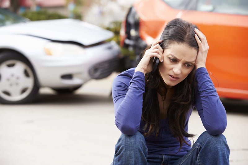 Woman Talking On The Phone With A Car Crash Scene In The Background